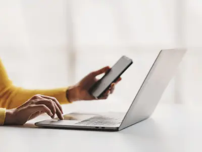 Hands on laptop with mobile phone