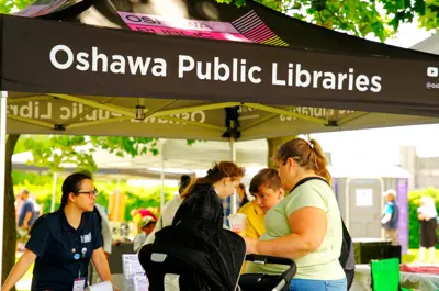 Oshawa public library tent set up with people doing activities at a table under the tent