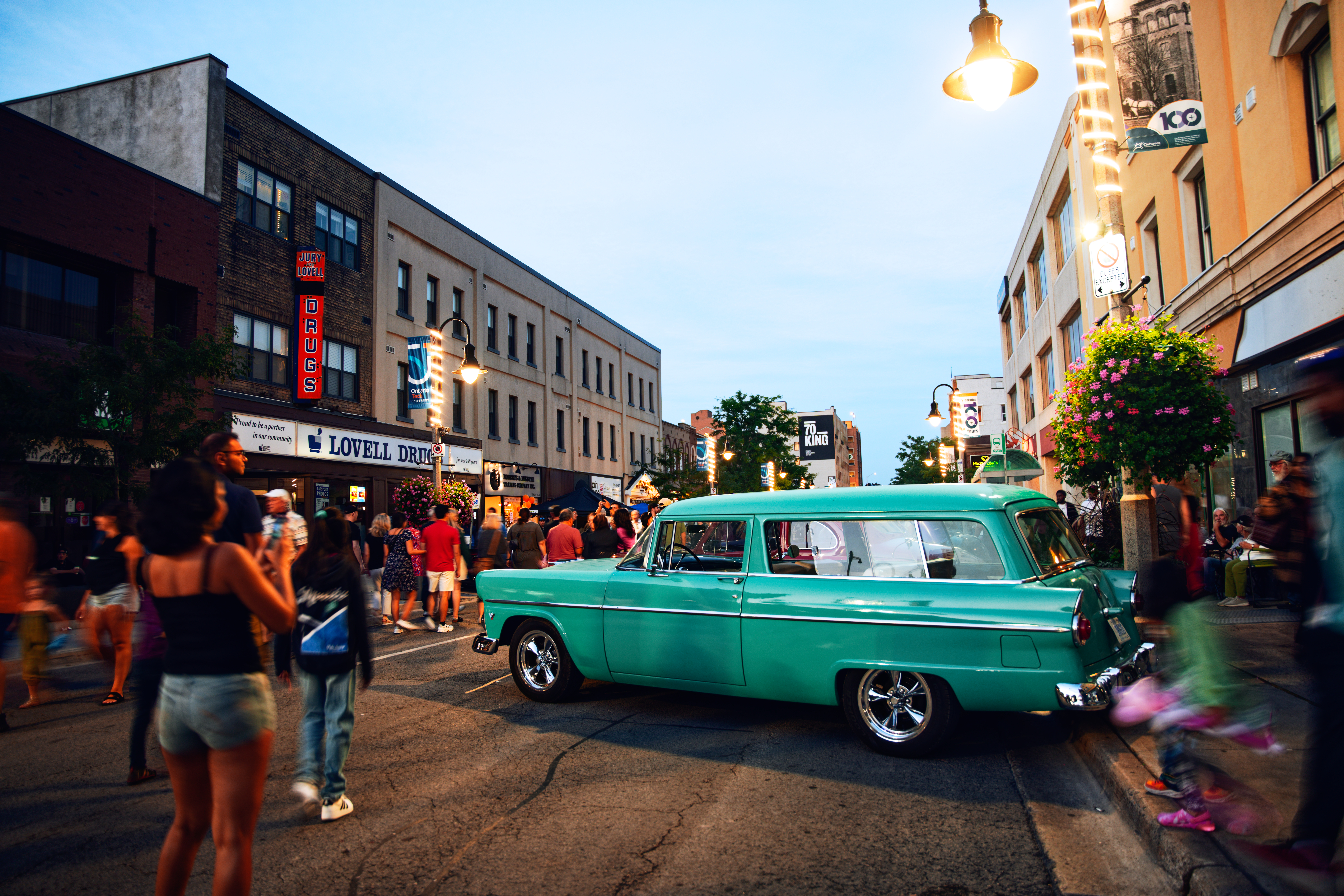 classic turquoise car on street with crowd, blurred for effect