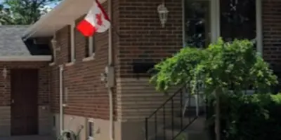 Corner view of a red brick house displaying a Canadian flag