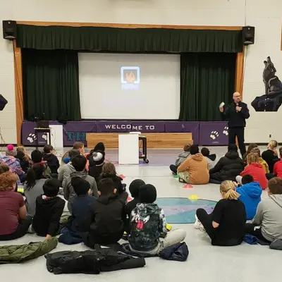 Fire prevention inspector presenting in front of children in a school audittorium