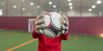 Person holding soccer ball in hand, while in fieldhouse