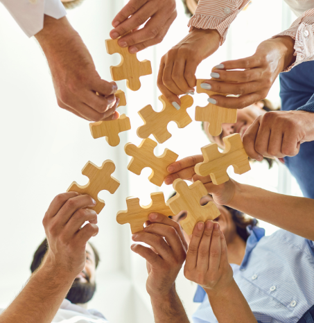 multiple hands in the circle holding large puzzle pieces