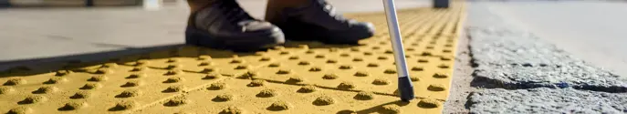 person using a cane at a tactile curb