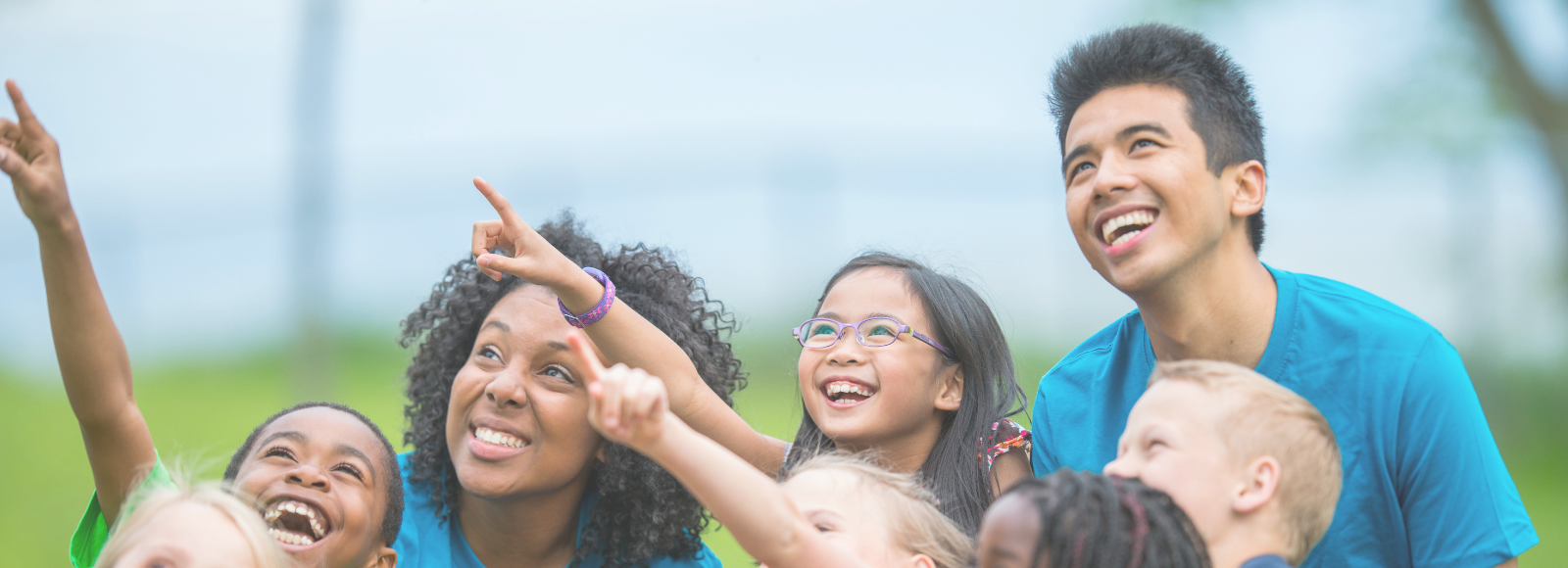 Adults with children outside looking and pointing up