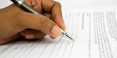 Hand holding a pen filling out a form