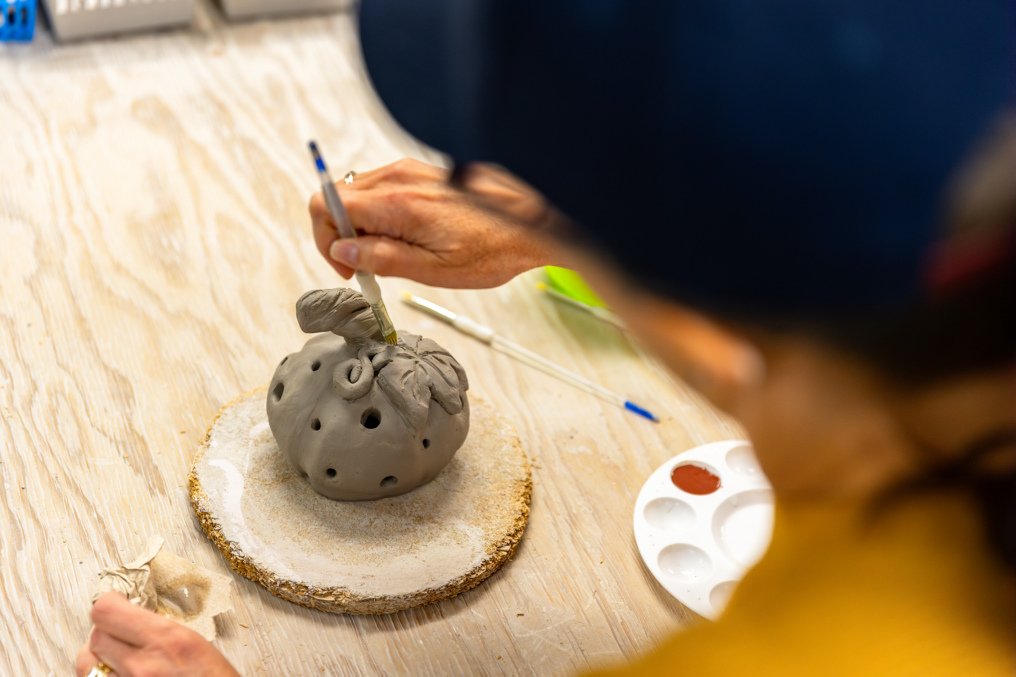 A person creating a pottery pumpkin