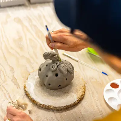 A person creating a pottery pumpkin