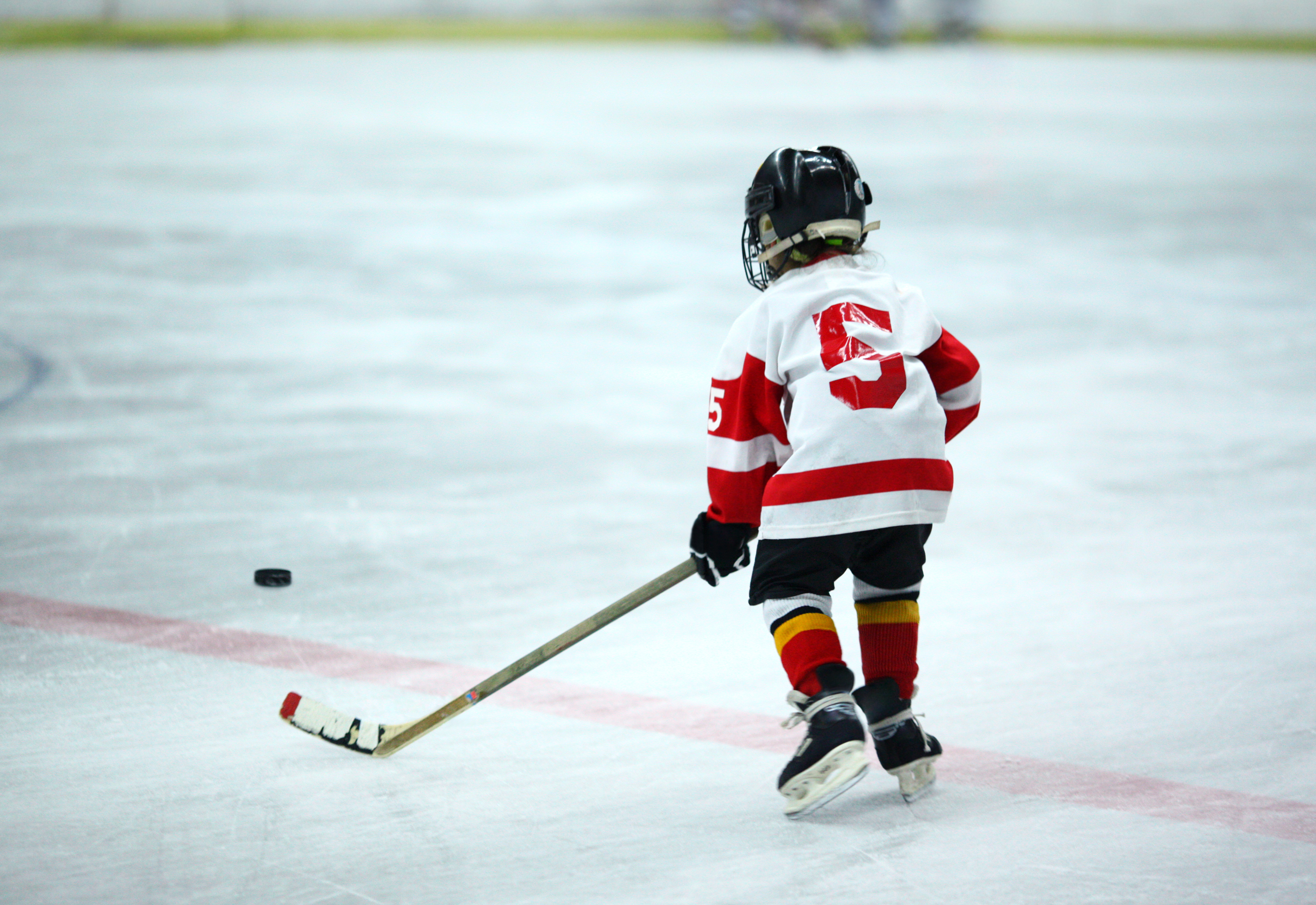 Child on ice carrying stick approaching puck