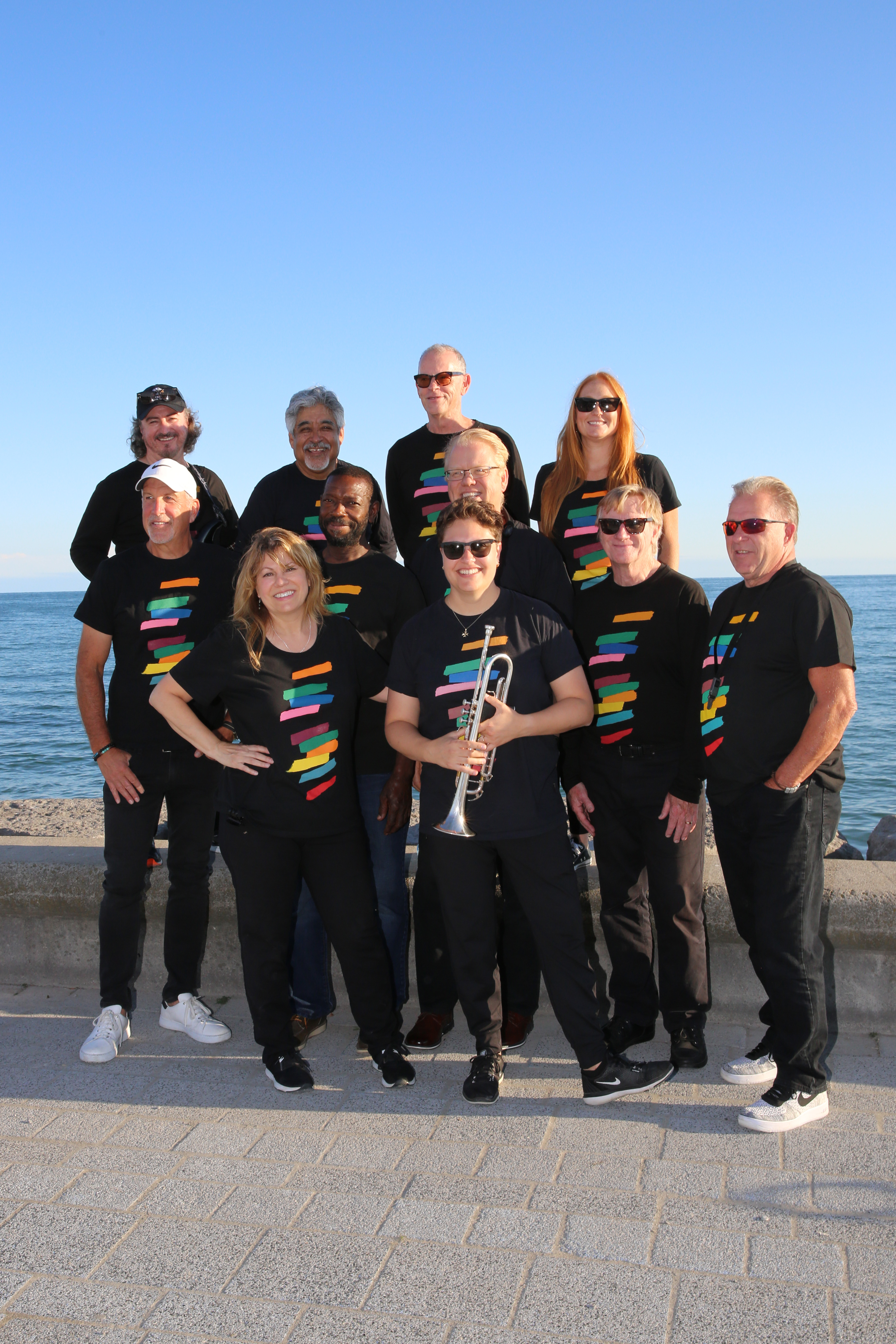 group of 11 band members standing in front of lake