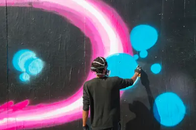 A street artist painting on the legal graffiti wall