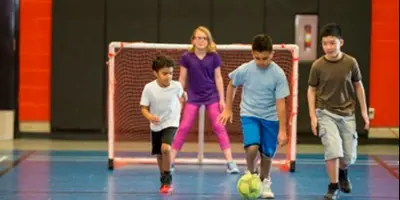 Kids playing soccer in gymnasium